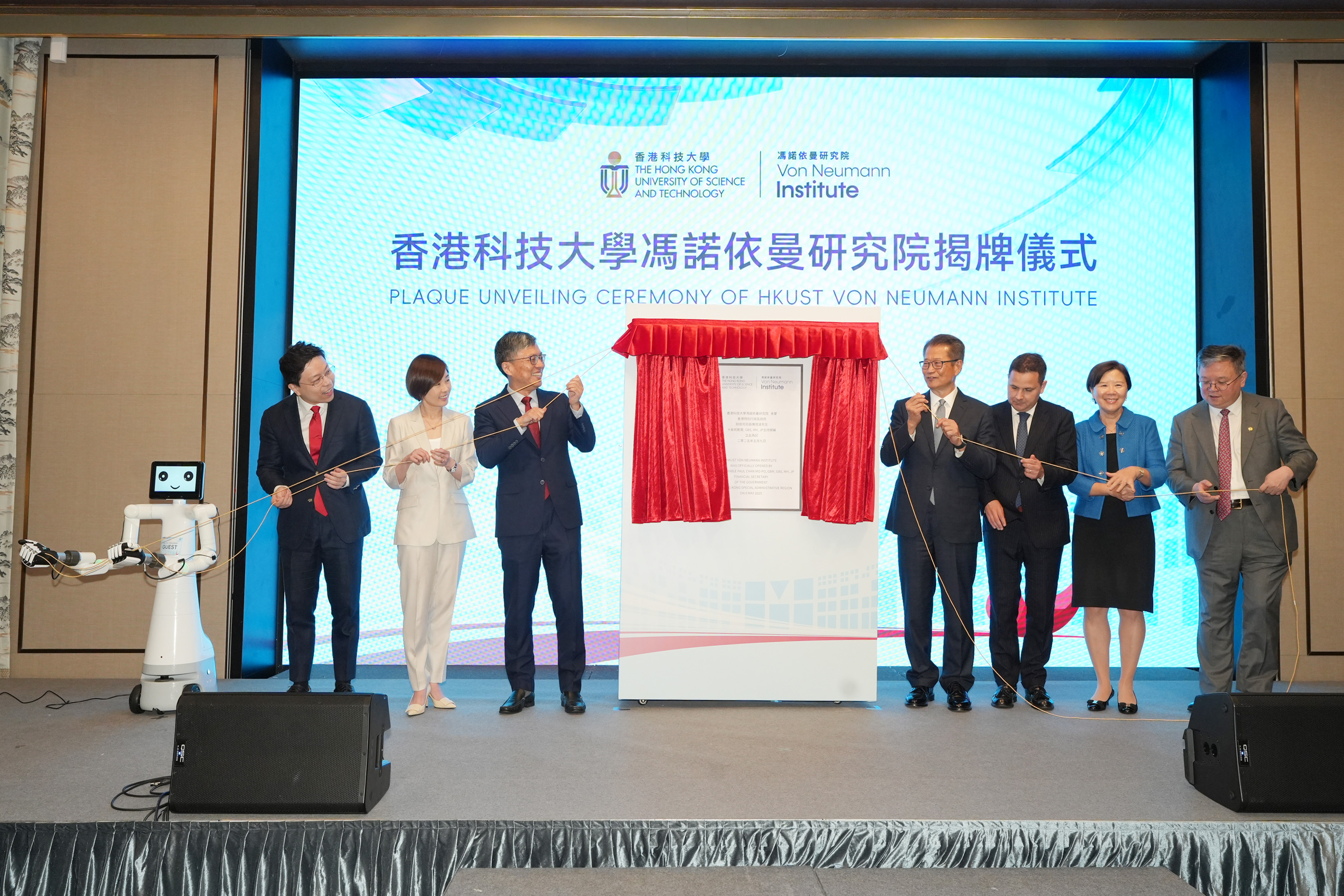 香港特别行政区财政司司长陈茂波（右四）、匈牙利驻香港总领事柯泰安（右三） 、香港投资管理有限公司（港投公司）行政总裁陈家齐（左二），科大校董会主席沈向洋教授（左三）、校长叶玉如教授（右二）以及首席副校长郭毅可教授（右一）等，会同科大冯诺依曼研究院（Von Neumann Institute）院长贾佳亚教授（左一）及其团队研发的AI机械人Vonnex，主持研究院的揭幕仪式。