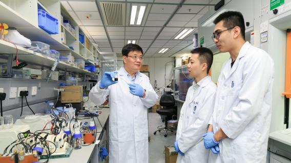 Prof. Zhao Tianshou (left) shows a sample of the e-fuel to his team members.