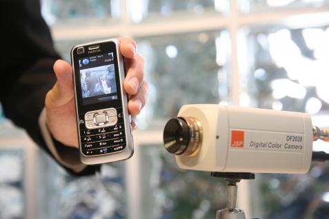 Contents from a surveillance camera are being fed into the mobile phone via a computer through streaming technology.	