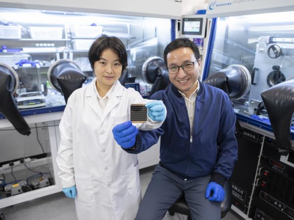 Prof. ZHOU Yuanyuan (right) and Dr. DUAN Tianwei (left) holding their newly developed perovskite solar cell.